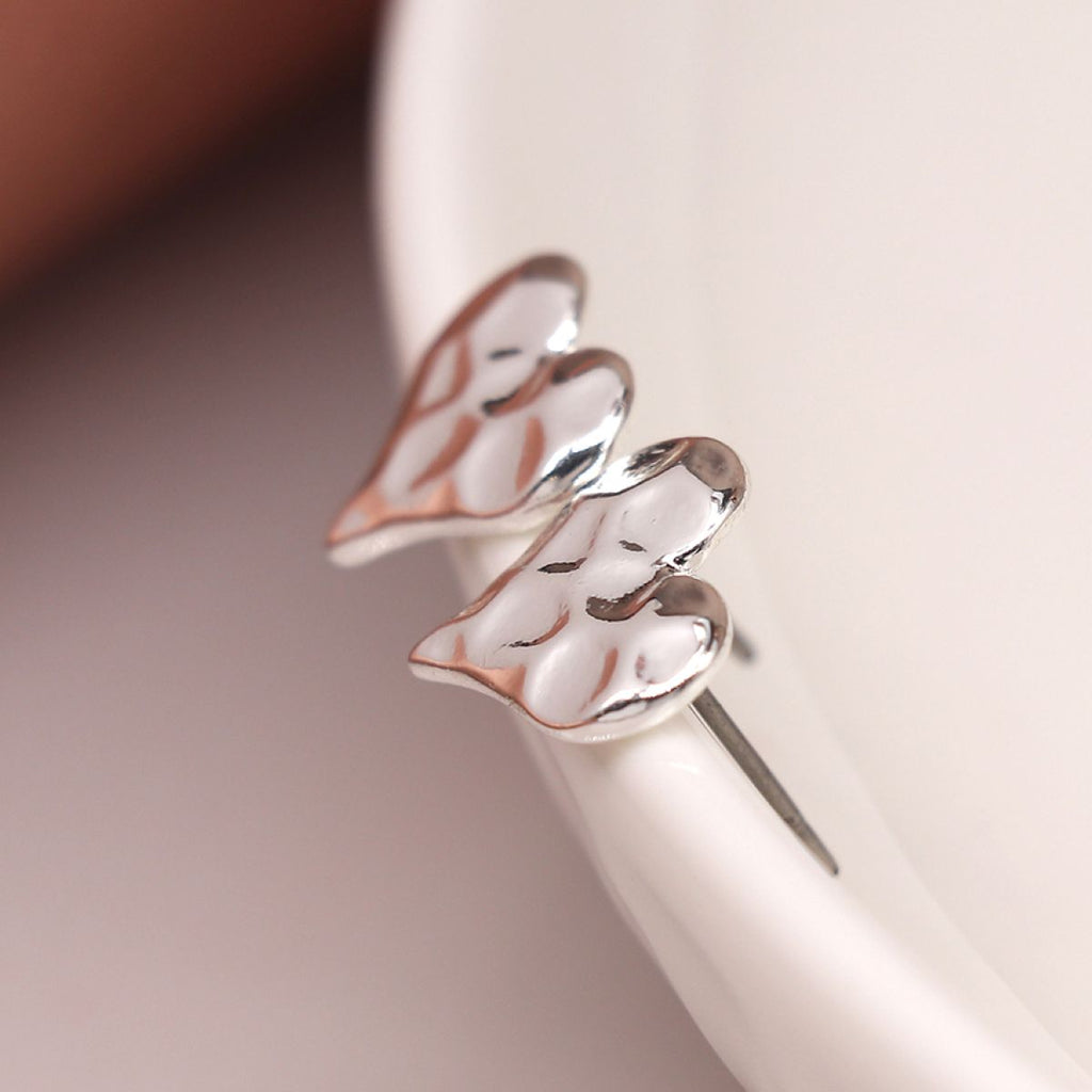 Silver hammered heart-shaped earrings on a ceramic dish display