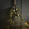 Decorative sparkly mistletoe hanging against a dark wooden background