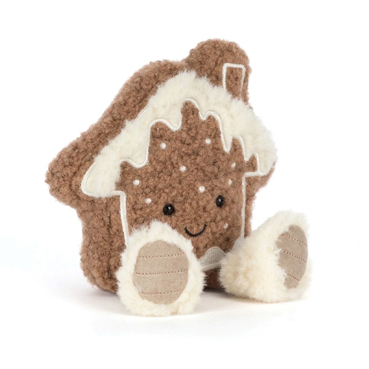 A plush gingerbread house toy with a brown curly-textured body, cream-colored icing details, embroidered facial features, and two small plush feet, photographed on a clean white background.