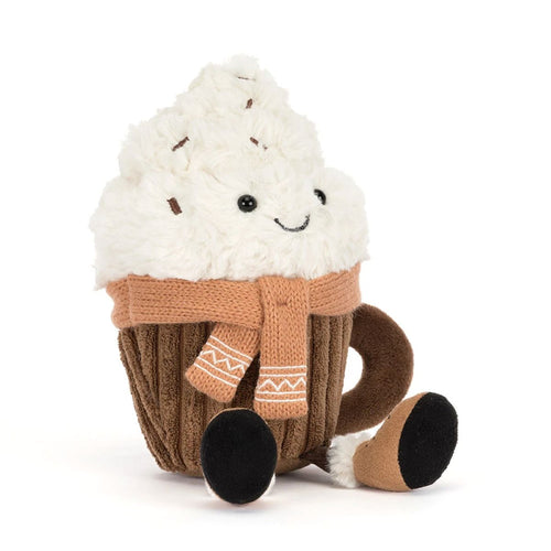 A plush brown mug with a swirl of cream on the top with brown sprinkles and a smiley face like a hot chocolate, has a beige knitted scarf wrapped around the middle. Small legs with black feet, shown on a plain white background.