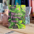 Book titled 'Witch's Forest' by Sandra Lawrence on a wooden surface with a blurred background