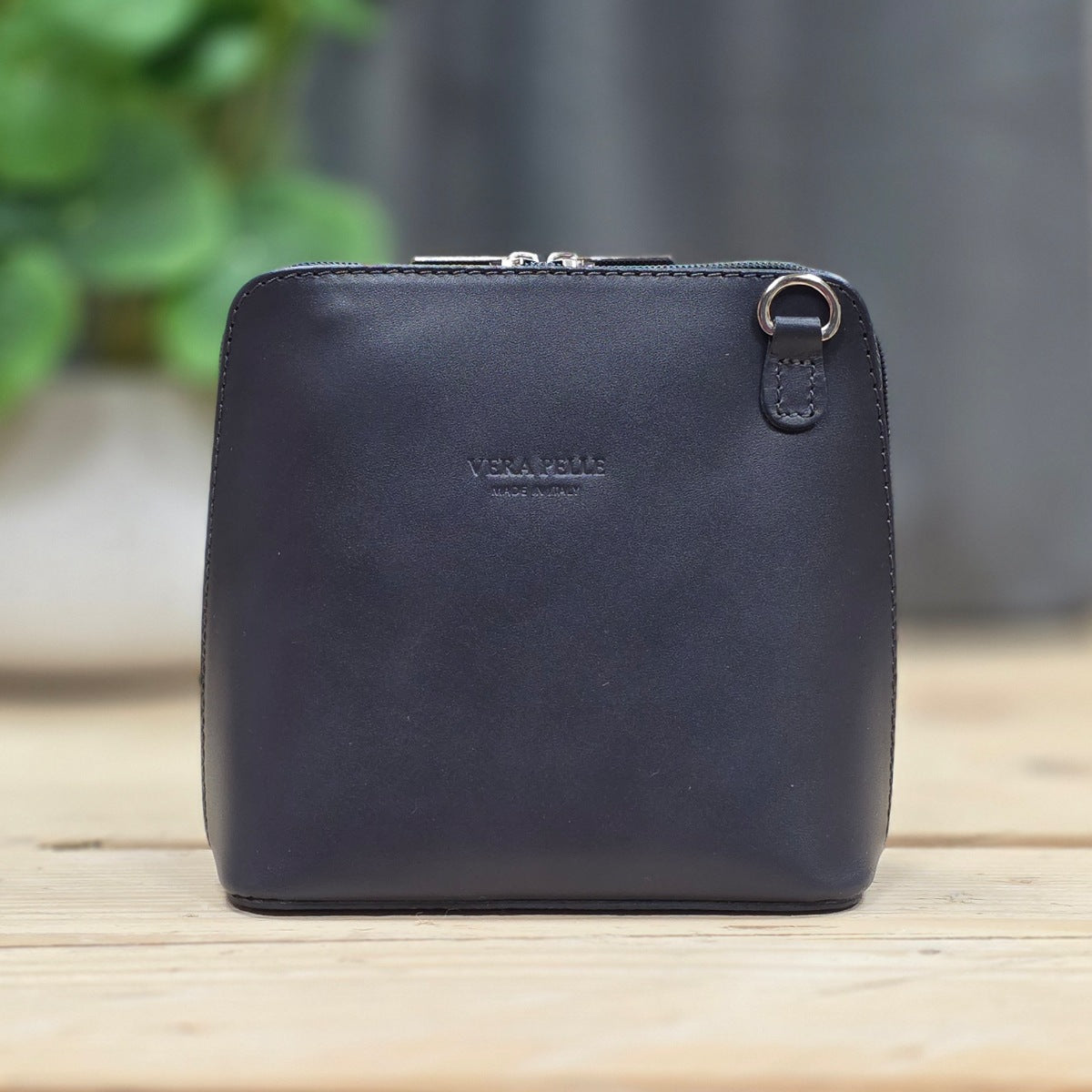 Dark grey leather handbag on a wooden surface.
