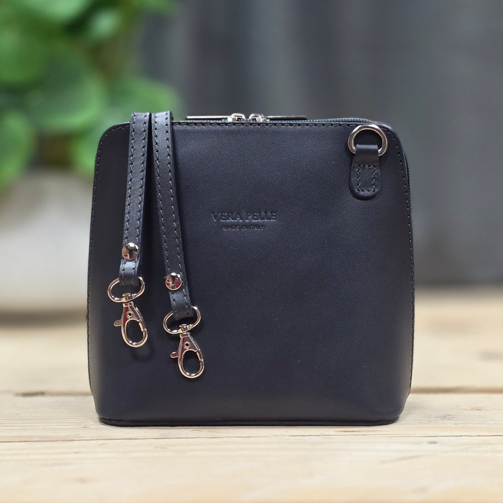 Dark grey handbag with detachable strap on a wooden surface