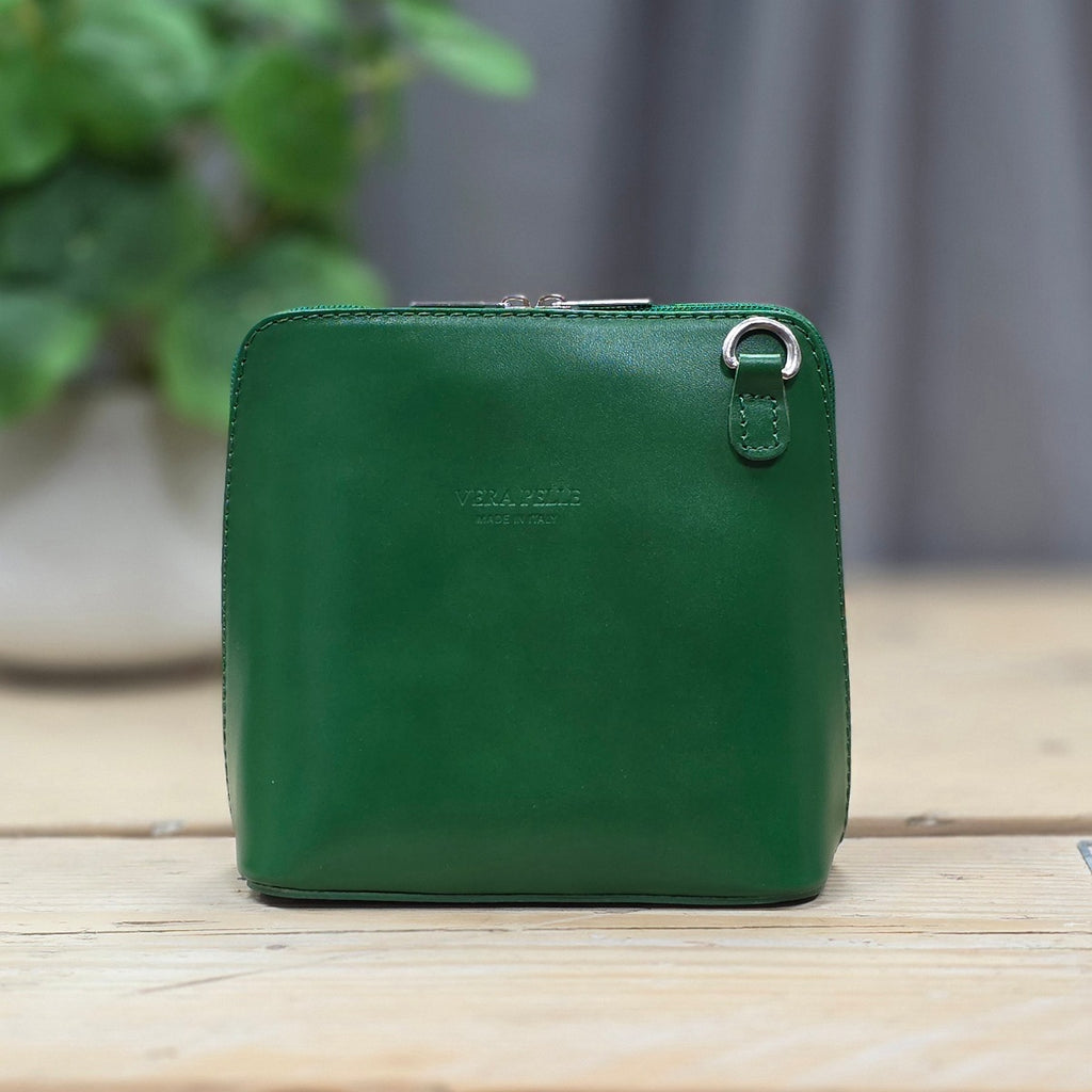 Green leather handbag on a wooden surface with a blurred background