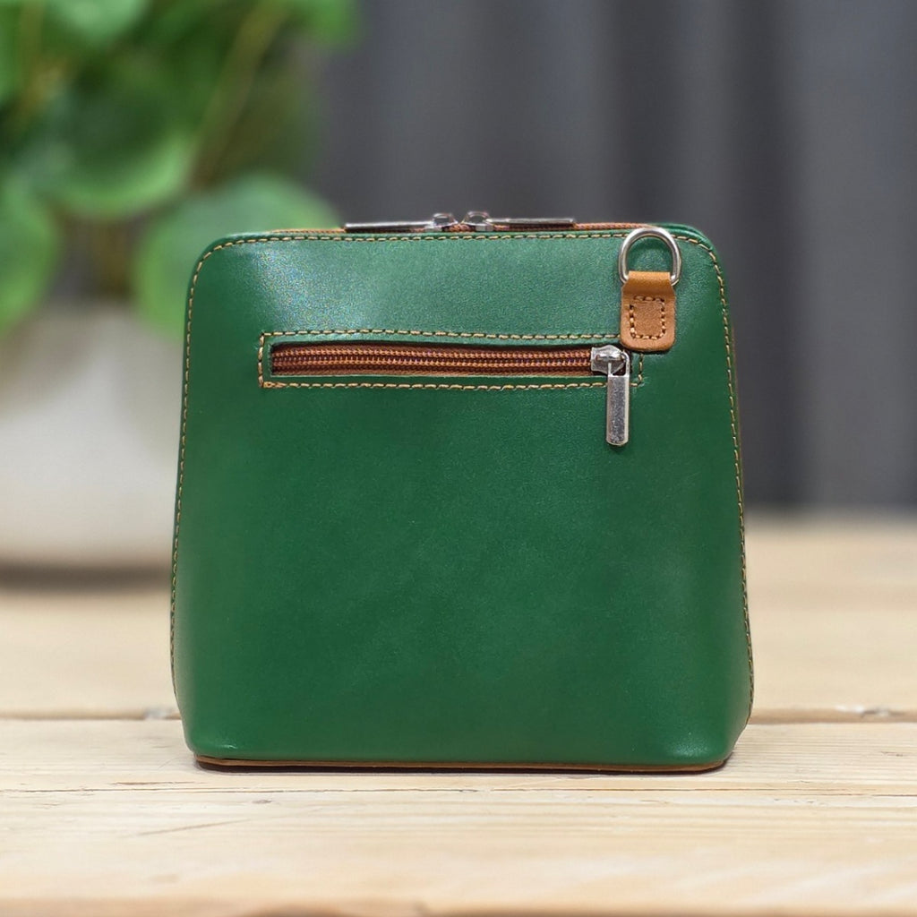 Green leather handbag with a zipper on a wooden surface