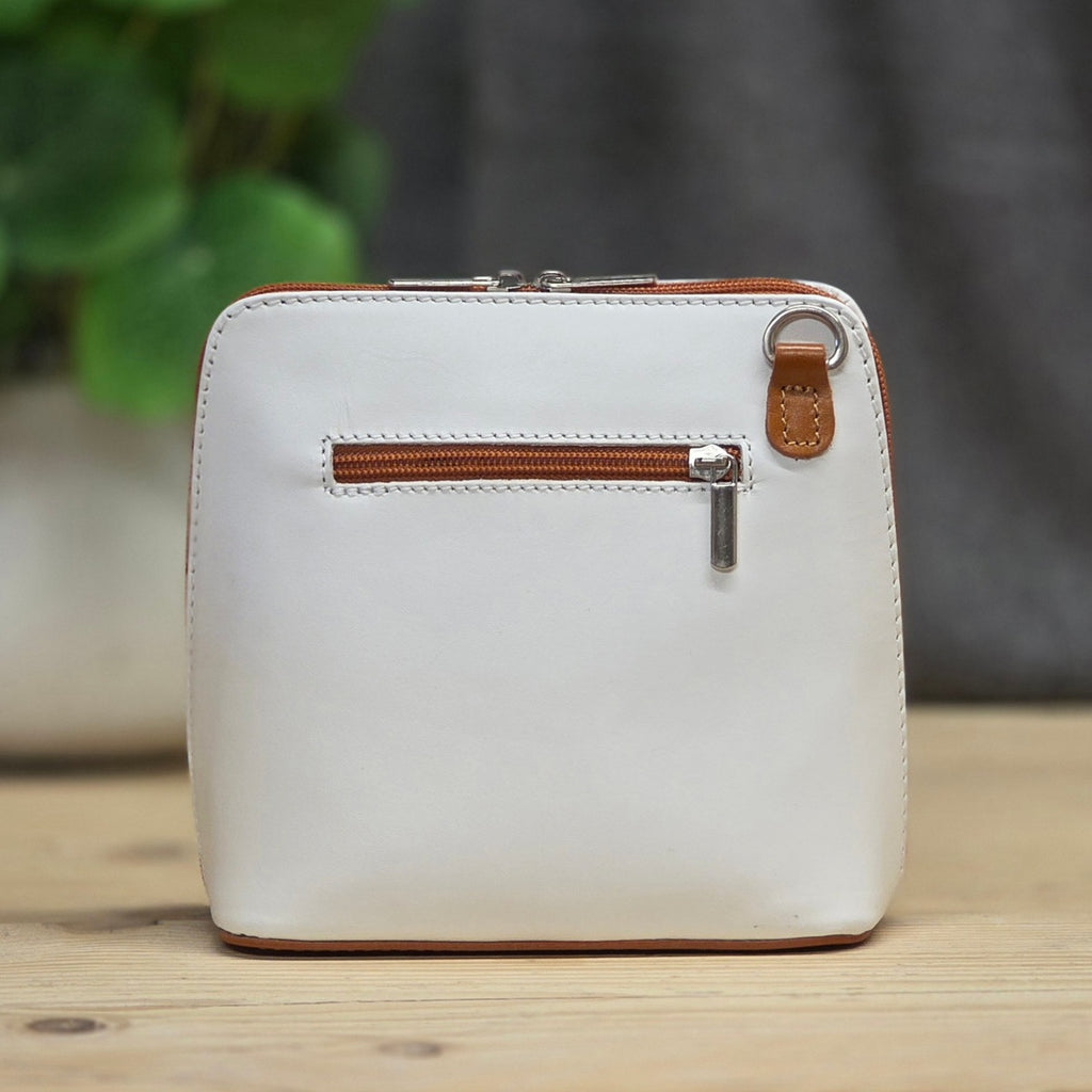 White leather bag with brown zipper on a wooden surface