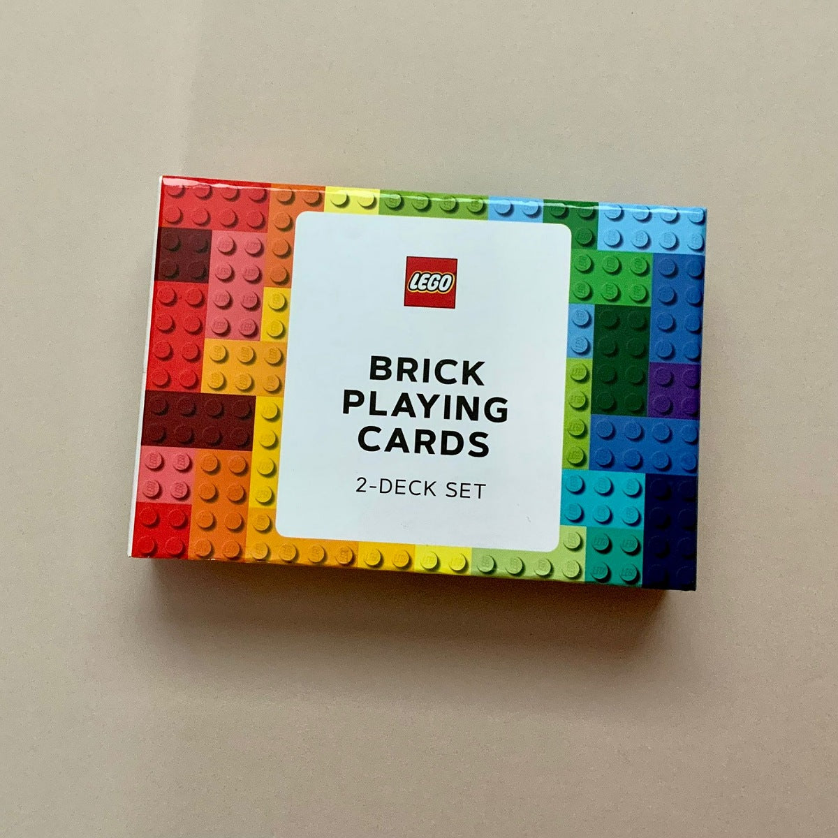 A box of LEGO Brick Playing Cards 2-Deck Set, featuring a colorful border resembling toy building bricks in a rainbow gradient around a white center label with the LEGO logo.