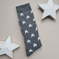 Dark grey folded sock with white star patterns on a beige background with decorative stars.