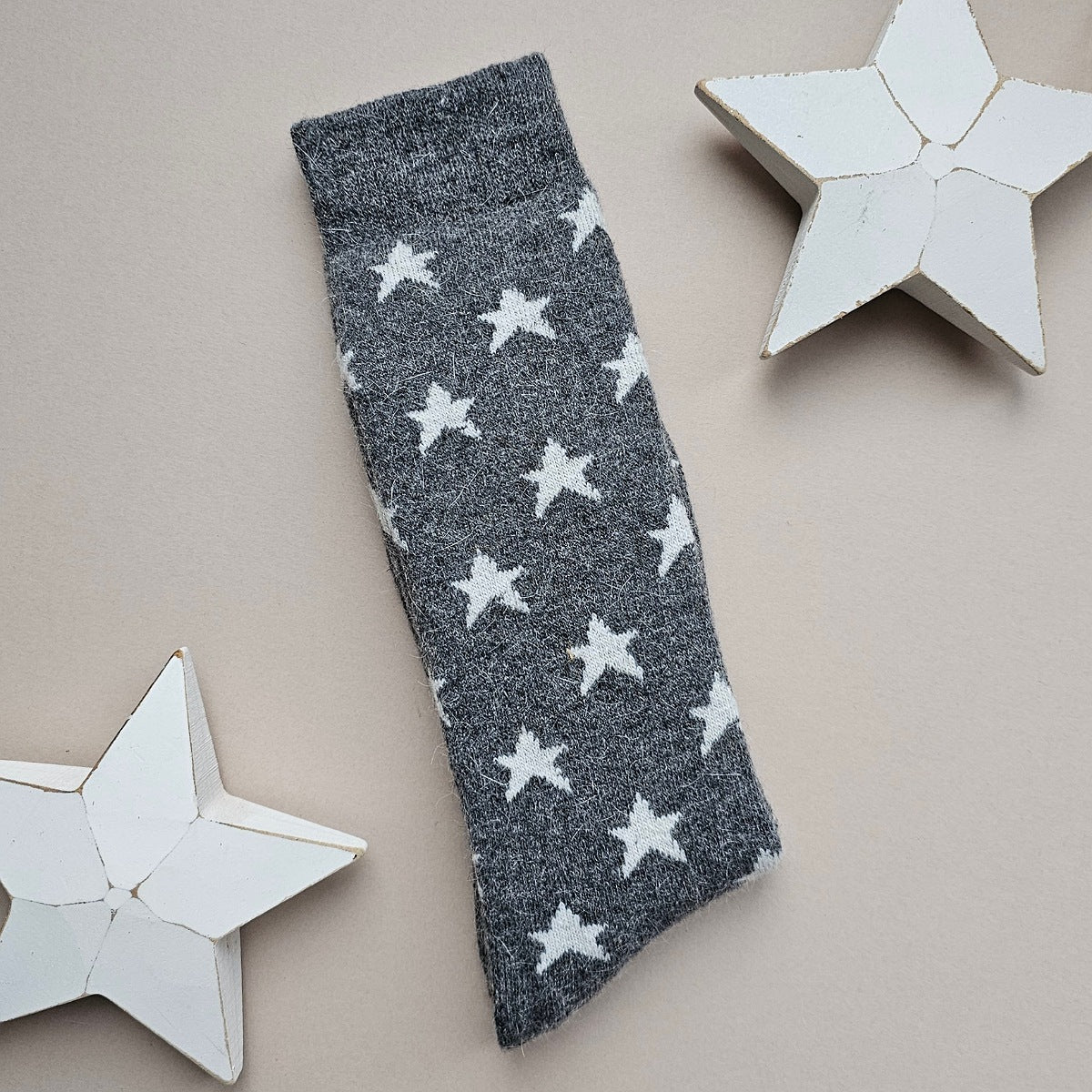 Dark grey folded sock with white star patterns on a beige background with decorative stars.