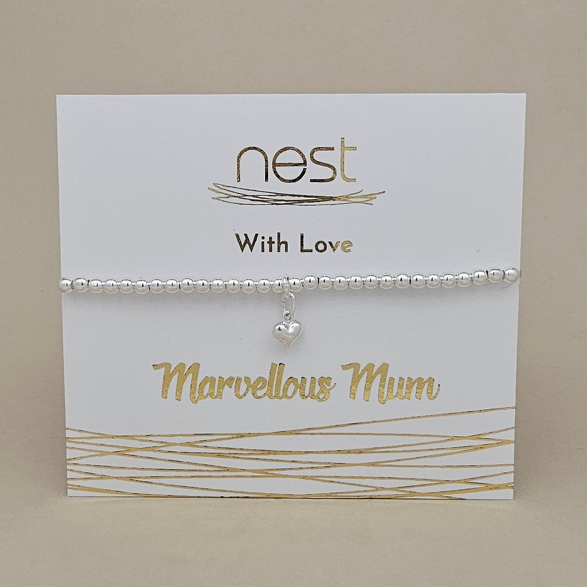 A silver beaded bracelet with a small dangling heart charm, displayed on a white gift card printed with the brand name 'nest' and the message 'With Love' and 'Marvellous Mum'.
