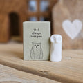 A small white ceramic owl figurine stands beside its light grey packaging box on a wooden surface. The box is printed with the words 'Owl always love you' and a black owl.