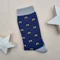 Navy blue sock with honey bee all-over pattern and silver grey cuffs and heel on a light surface with two white star decorations