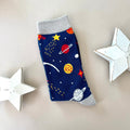 A single navy blue sock with a colourful space-themed print of planets, stars, and rockets with light grey cuff, heal and toe.  Styled on a light grey background with two white star-shaped props.