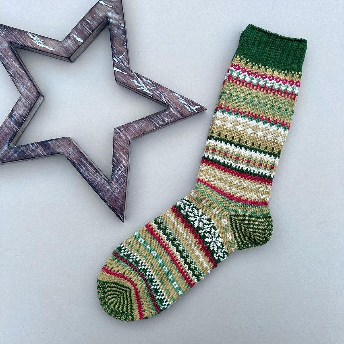 Colorful knitted socks in shades of green and red with pattern on a white background
