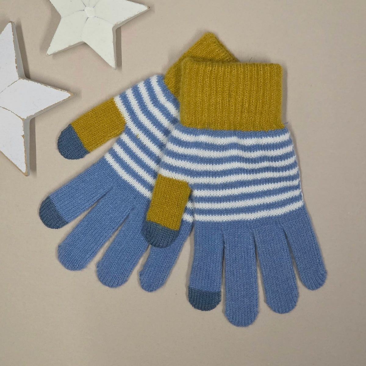 Pair of blue and mustard yellow striped gloves on a beige background