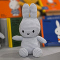 Gray plush bunny toy with a blurred store shelf in the background