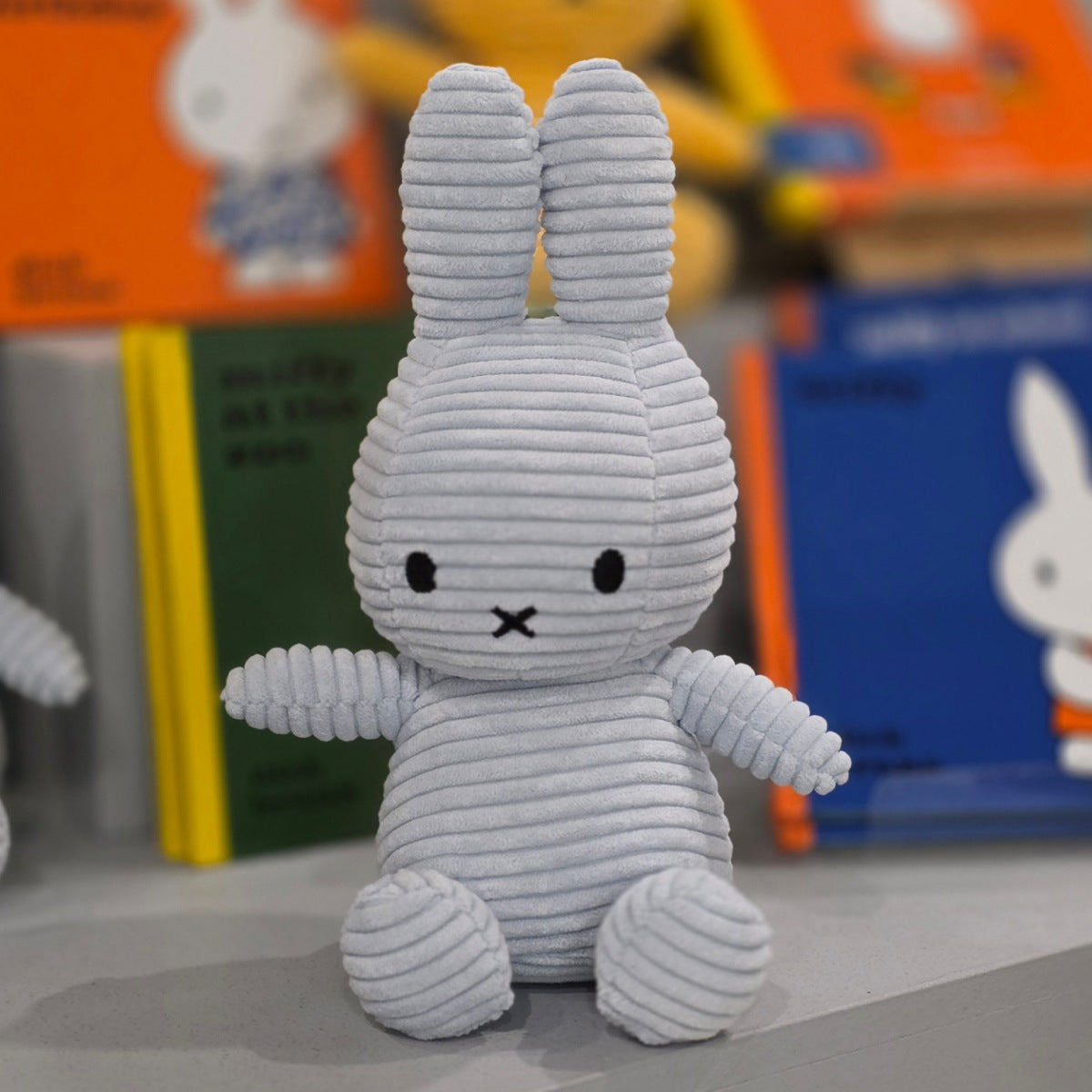 Gray plush bunny toy with a blurred store shelf in the background