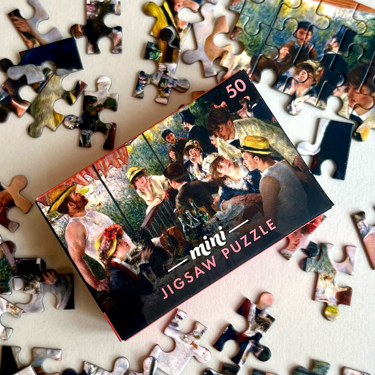 Mini jigsaw puzzle box with puzzle pieces scattered around