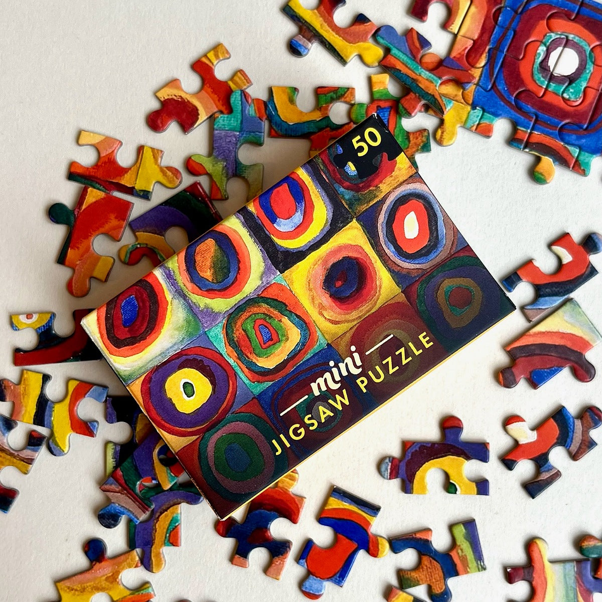 Miniature jigsaw puzzle with colorful design and scattered pieces on a light background
