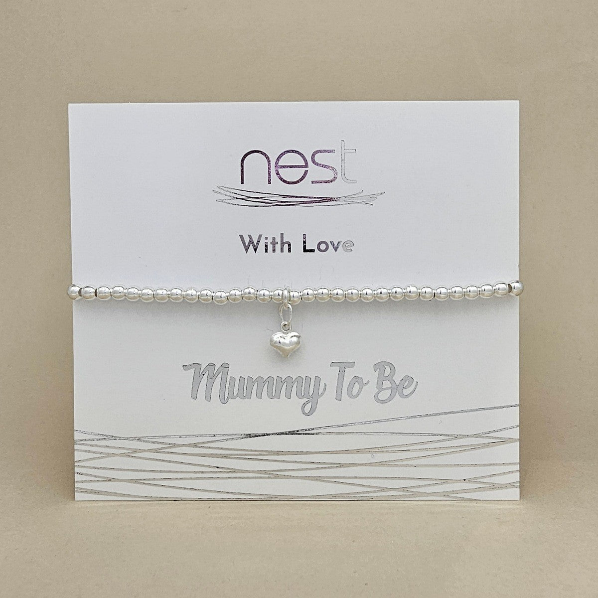 A silver beaded bracelet with a small heart charm, displayed on a white card that reads 'nest With Love' and 'Mummy To Be'.