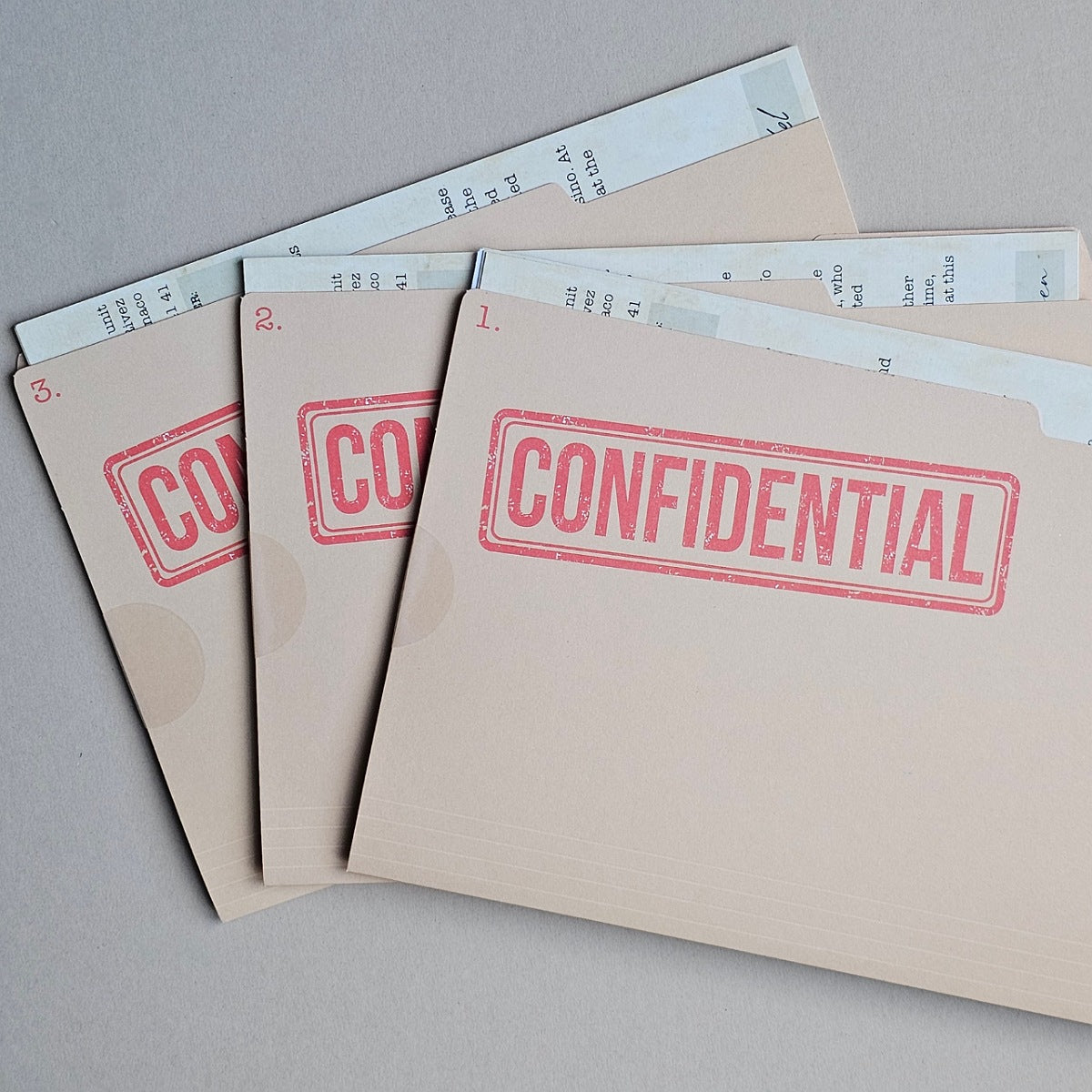 Four beige confidential folders arranged in a fan shape on a neutral grey background, each stamped with 'CONFIDENTIAL' in red ink.