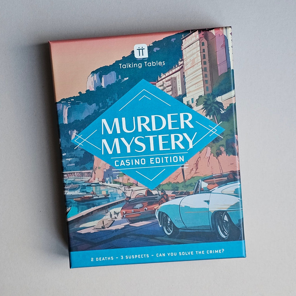 Murder Mystery Casino Edition card game box, featuring a retro coastal city illustration with a blue diamond logo and a light blue convertible car on the cover, photographed on a neutral grey background.