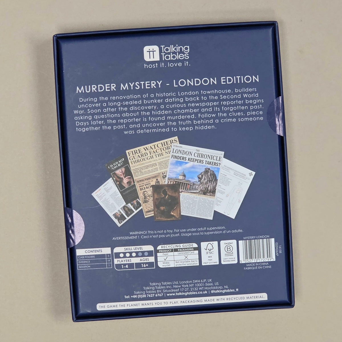 The back of the 'Murder Mystery - London Edition' game box, photographed from above on a neutral beige surface. The box is dark blue with white text and a small newspaper collage graphic.