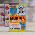 Muddle Junior 2 puzzle book by G.T. Karber on a wooden surface with a blurred background