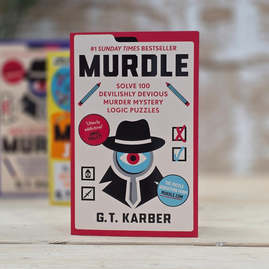 Book titled 'Murdle' by G.T. Karber, to solve 100 devilishly devious murder mystery logic puzzles on a wooden surface with blurred background