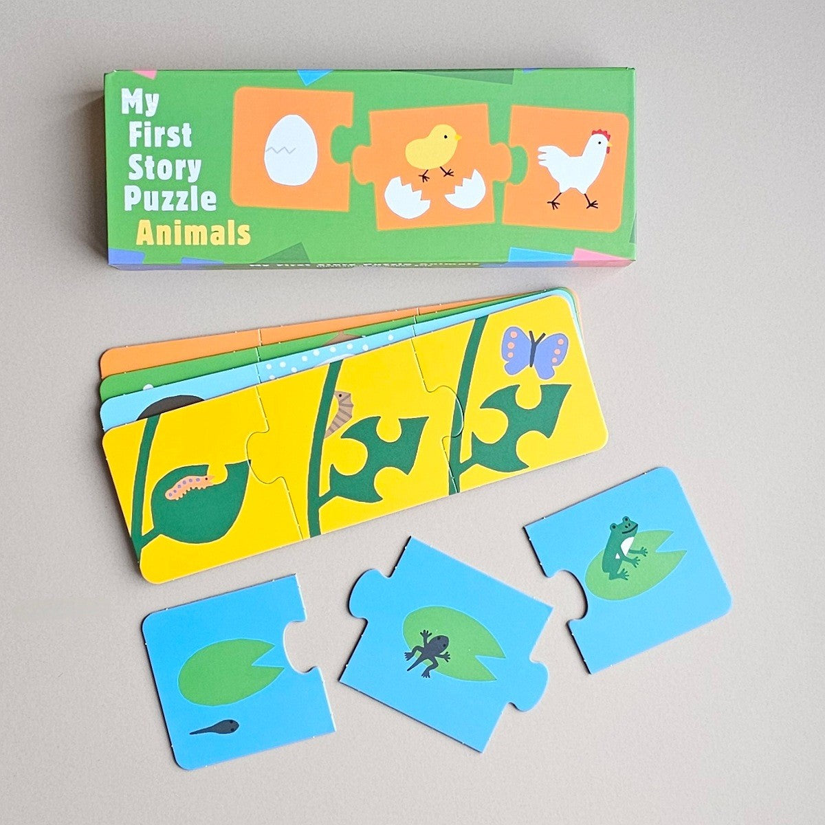 My First Story Jigsaw Puzzle Animals with a green box, a yellow puzzle strip, and several blue animal puzzle pieces on a light grey background.