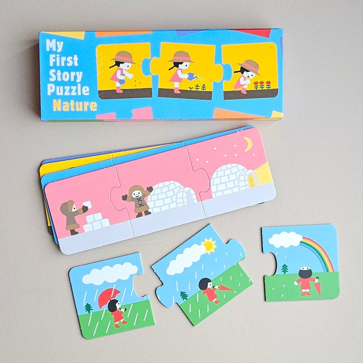 A children's wooden puzzle book set titled 'My First Story Puzzle Nature' shown with its colorful box, an unfolded stack of puzzle pieces, and three loose puzzle pieces on a light grey surface.