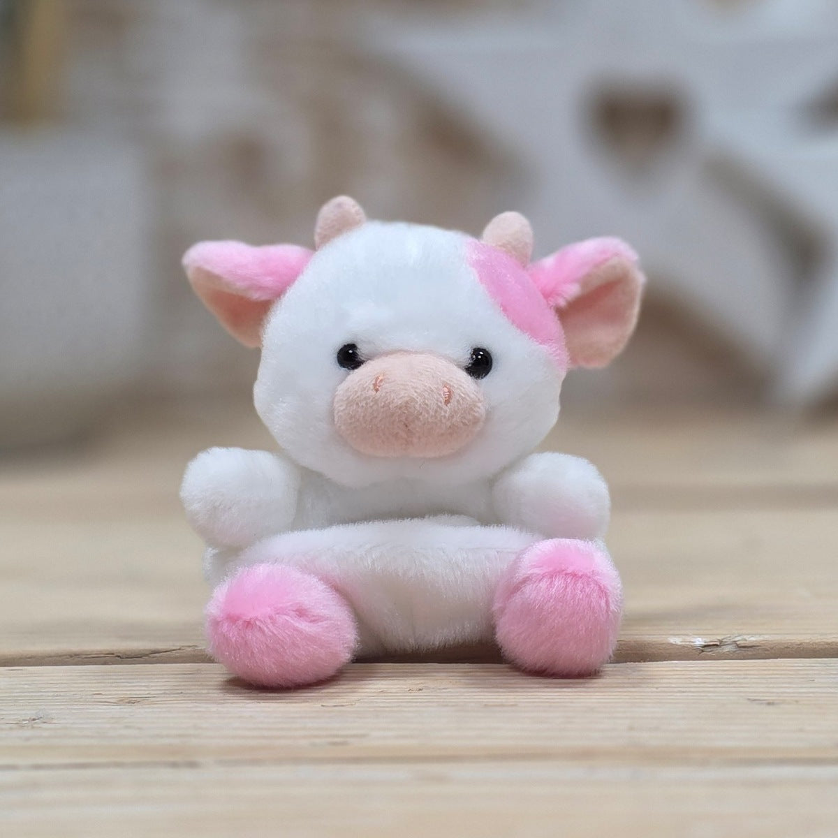Plush toy pig with pink accents on a wooden surface
