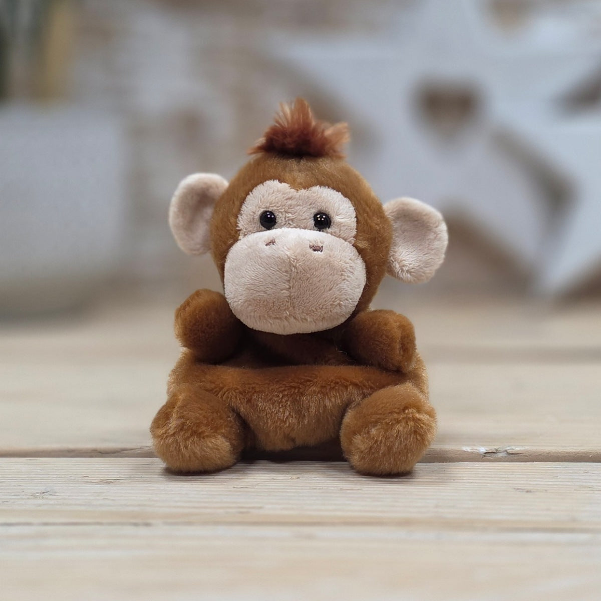 Plush monkey toy on a wooden surface with a blurred background