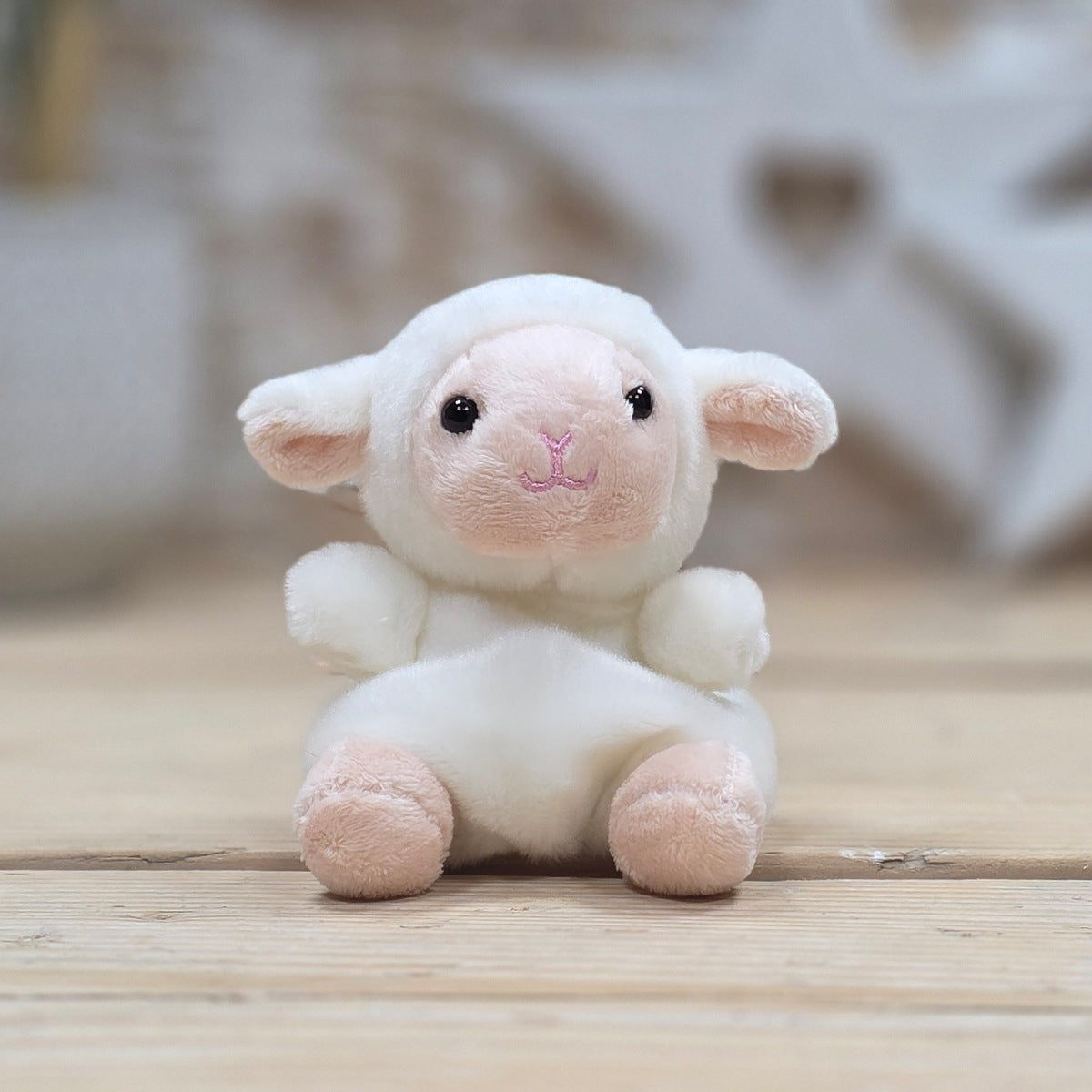 Plush toy sheep on a wooden surface with a blurred background