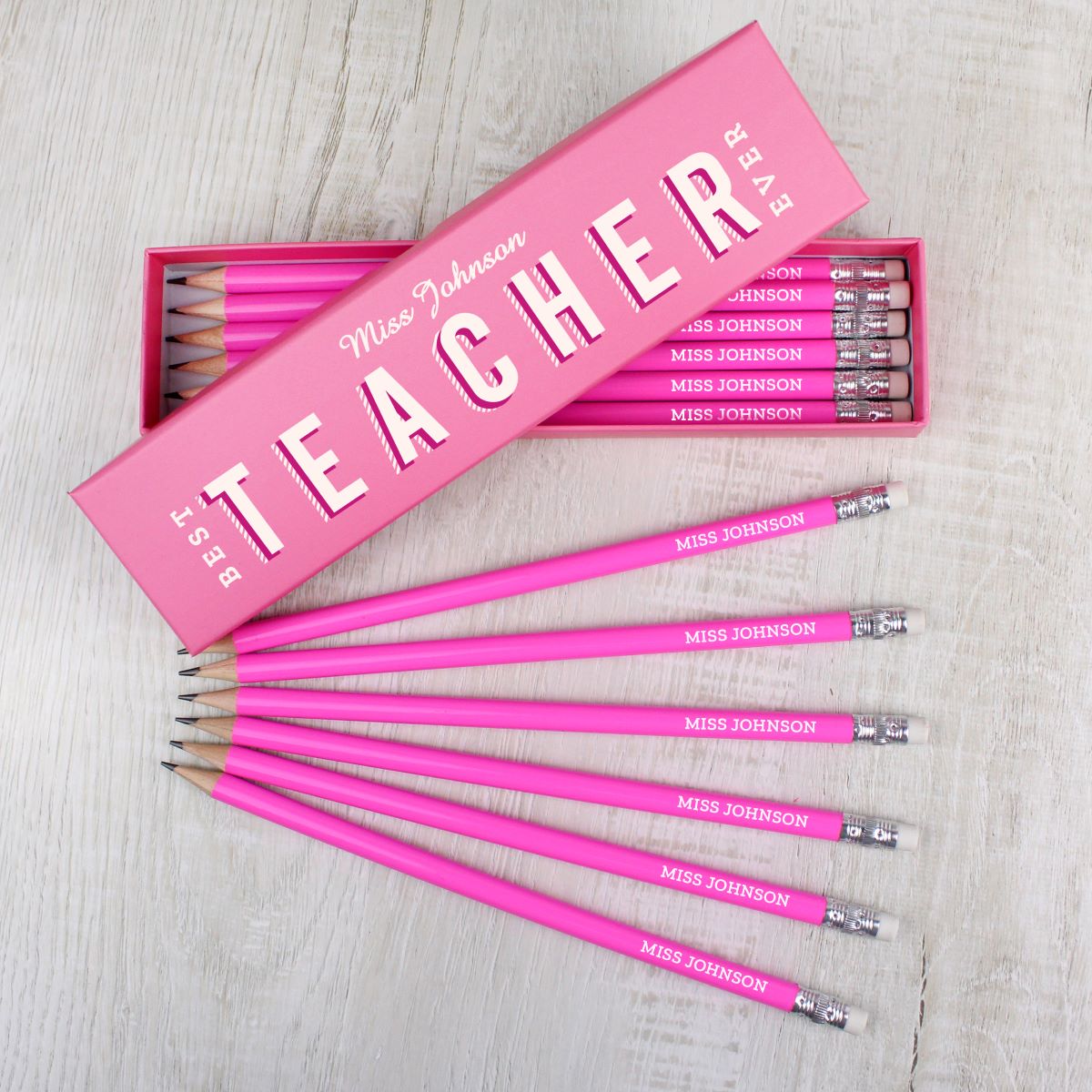 Pink pencils with 'Miss Johnson' engraved on each pencil on a light wooden surface