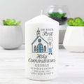 White candle with a printed design of a church and a boy, on a white surface with plants in the background.
