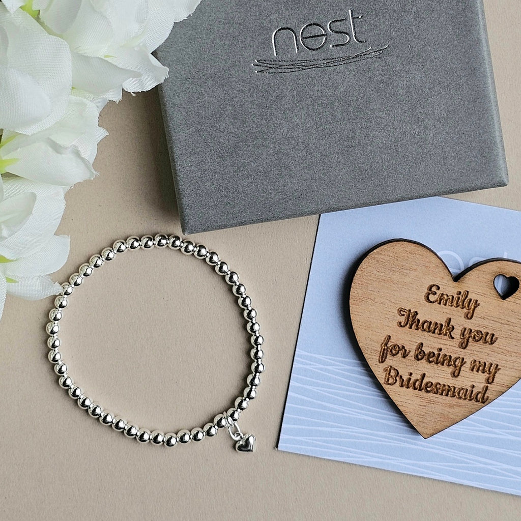 Silver bracelet, wooden heart with 'nest' box and card on beige surface