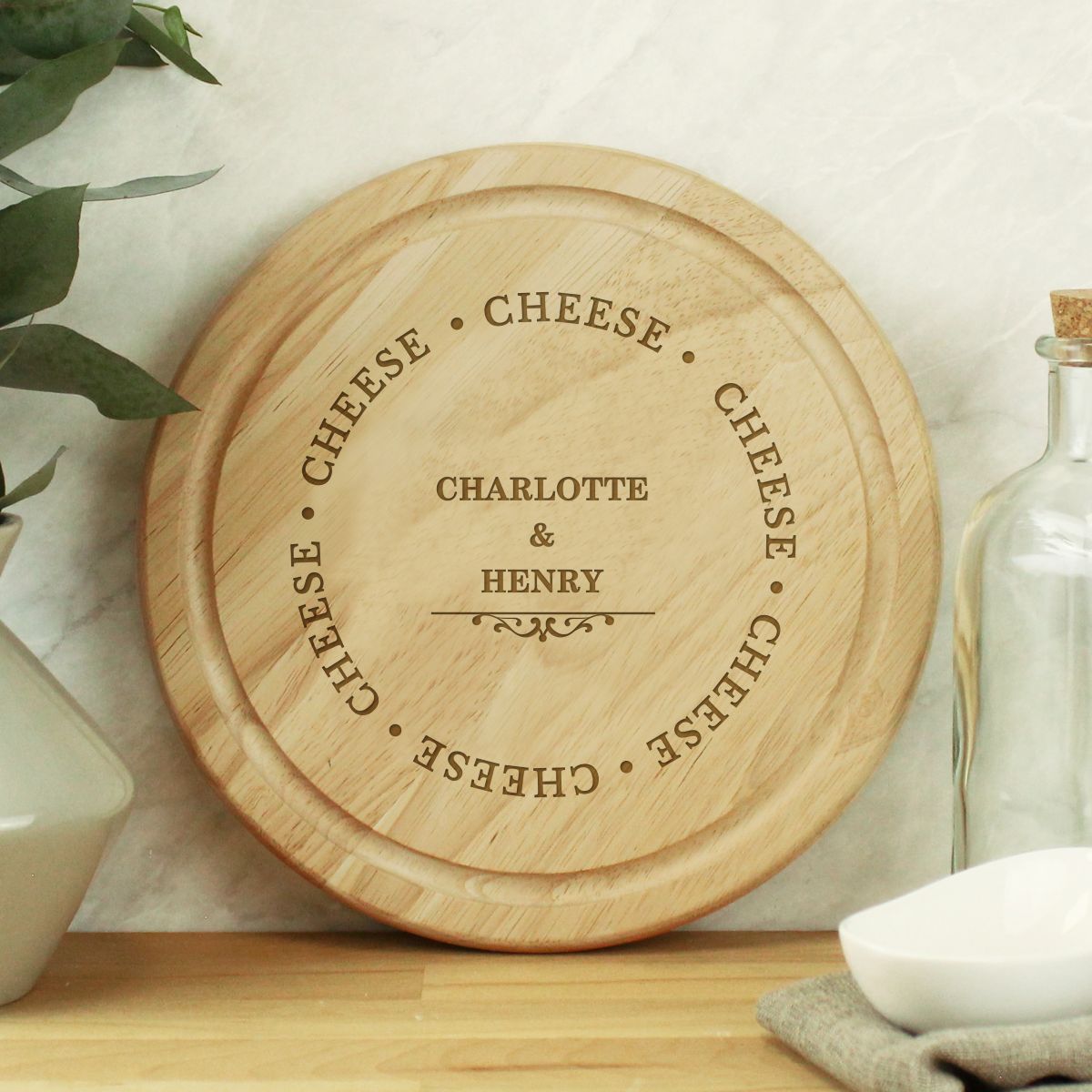 Wooden cheese board with engraved text on a kitchen counter.