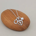 Silver necklace with heart and cross pendant on a wooden rock