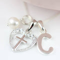 Silver necklace with heart pendant, cross, and letter 'C' on a white background