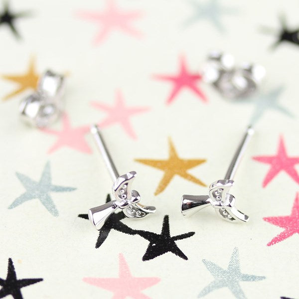 Silver bow stud earrings shown from the back on a light cream background with colorful star confetti.