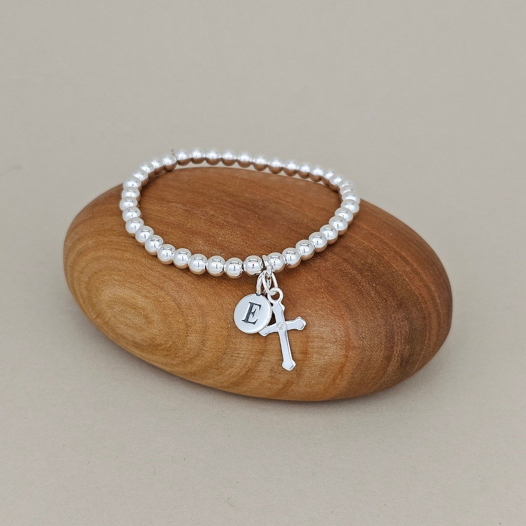 Silver bracelet with a silver charm on a wooden rock