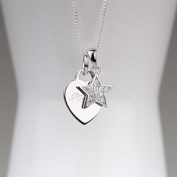 A silver pendant necklace featuring a heart and star charm, displayed on a white mannequin bust. The star charm is embellished with small clear crystals, and the heart charm has a subtle engraving.