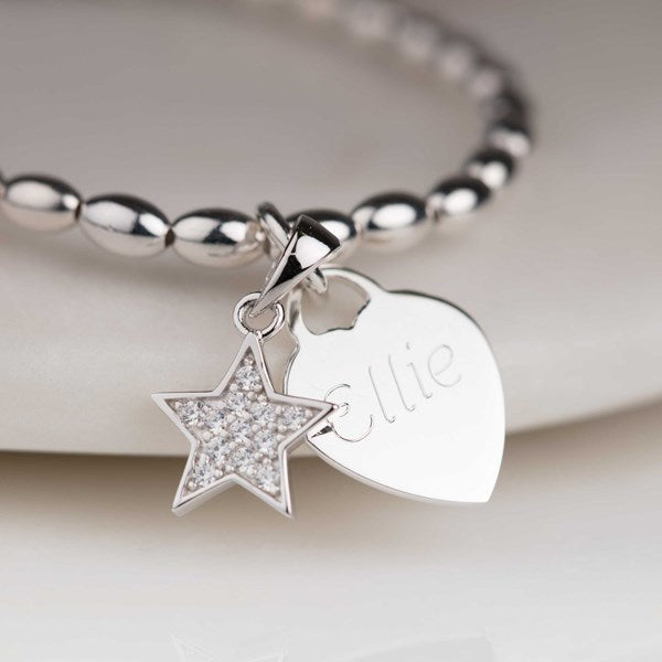 Silver bracelet with star and heart charm on a white background