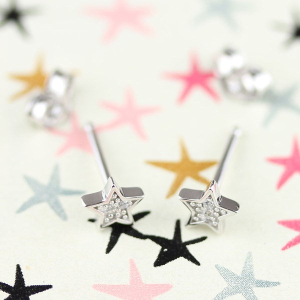 Silver star shaped earrings on a star design background.