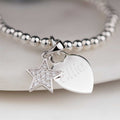 Silver bracelet with star and heart charm on a light background