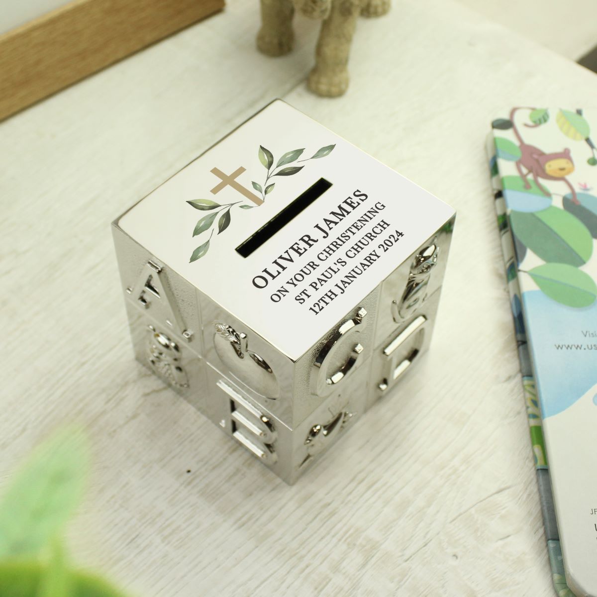 Personalized silver money box with engraved text on a wooden surface