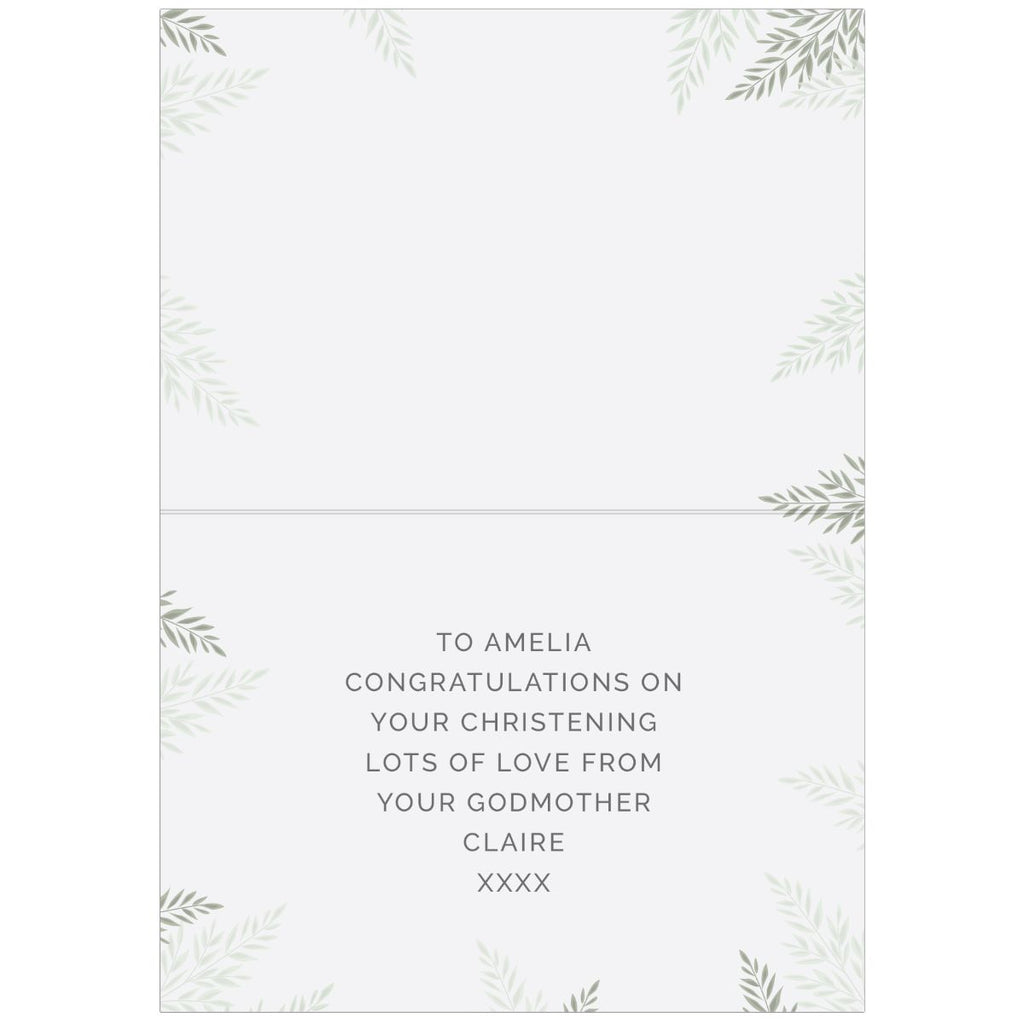 A folded greeting card with a white background, featuring delicate gray-green leaf illustrations in the corners and a printed message on the lower half: 'TO AMELIA CONGRATULATIONS ON YOUR CHRISTENING LOTS OF LOVE FROM YOUR GODMOTHER CLAIRE XXXX'.