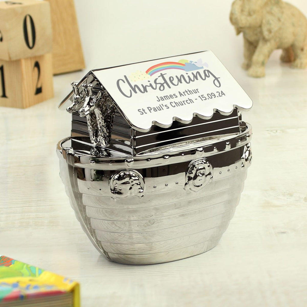 Decorative money box with 'Christening' text and rainbow design on a wooden surface.