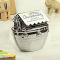 Decorative money box with 'Christening' text and rainbow design on a wooden surface.